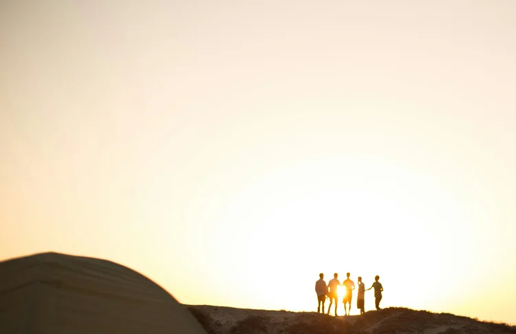 Silhouettes of people standing on a hill at sunset