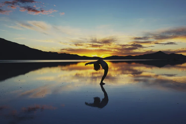 A dancer silhouetted at sunset on a lake